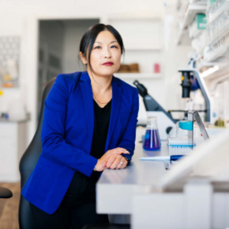 woman sitting next to microscopes